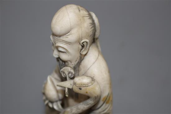 A Chinese carved ivory group of a sage holding a peach, seated beside a crane and a deer, 17cm